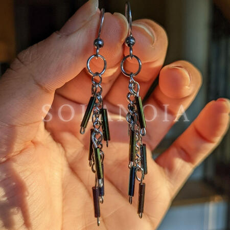 nova earrings glistening in golden sunlight. shining reflective iridescent fairy earrings. 2 inch long earrings. stainless steel earring hooks